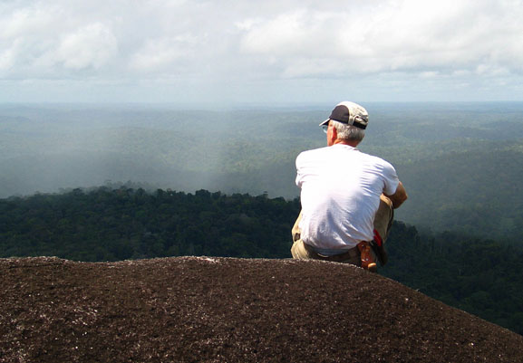 The author looking south from a granitic outcrop in French Guiana into Brazil. There is still opportunity to project forest like this even though a lot has already been lost. (Photo by N. Pitcairn)