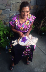 Juana embroidering a beautiful sunflower in a scarf.