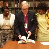 Image of a Library professional showing a book to students.