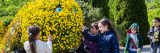 Children looking at a sculpture of a caterpillar with yellow flowers