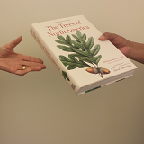 Photo of one person handing a book to another person