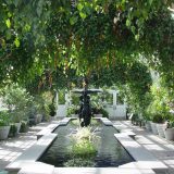 An indoor water fountain surrounded by lush greenery hanging from the ceiling.