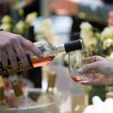 Wine is poured into a glass in front of a backdrop of iced wine bottles and daffodils.