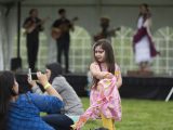 Little girl dancing with face paint on in front of a band.