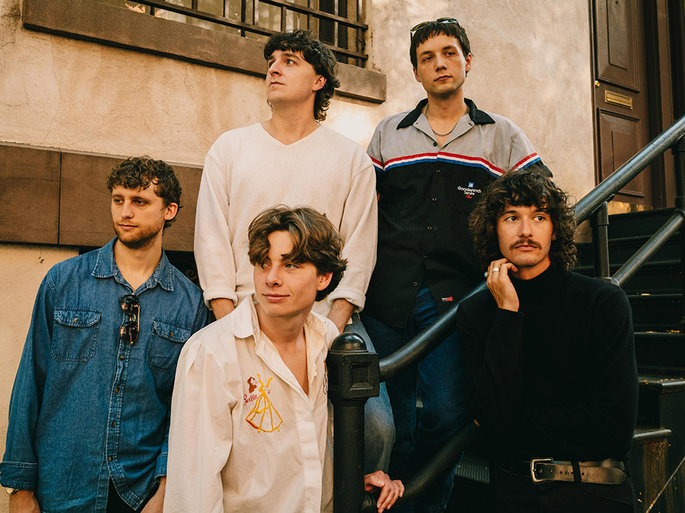 A group of five people pose on a staircase for a band photo