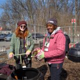 NYC Compost volunteer showing guest how to work with composted food scraps.