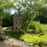 Summer image of the Stone Mill from the bridge over the Bronx River.