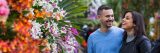 A couple walking by colorful flowers during Orchid Evenings