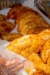 A close-up of a golden fried food item being held by a person wearing a clear glove