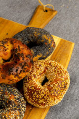Four bagels covered in seeds, sitting on a cutting board