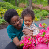 A parent and child look at vivid fuchsia flowers outdoors