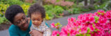 A parent and child look at vivid fuchsia flowers outdoors