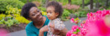 A parent and child enjoying themselves in a garden of pink flowers