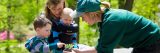 A staff member showing a plant to a mom with two children