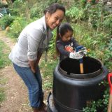 BGU Staff showing a small girl how to compost in a bin.