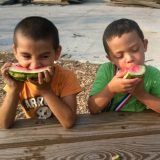 Two young boys enjoying watermelon from a community garden