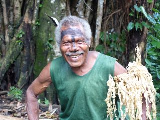 Man with face paint holding dried ferns