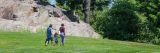 three visitors walking along the green grass of daffodil hill in the summer