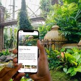 man holding a phone displaying bloomberg connects in front of holiday train show building