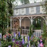 A bed of purple, blue, and pink flowers in front of the cottage in the Conservatory.