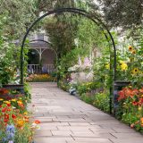 A trellis surrounded by vibrant and colorful flowers facing right.