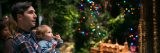 A man holding a baby looking at the Holiday Train Show displays