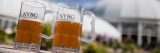 Two beer glasses in front of the Enid A. Haupt Conservatory.