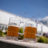 Two beer glasses placed in front of the Enid A. Haupt Conservatory.