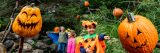 Photo of a boy in a pumpkin costume pointing at a scarecrow pumpkin in the Spooky Pumpkin Garden