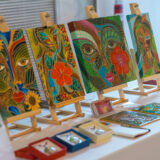 An arrangement of colorful paintings and jewelry for sale