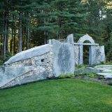 Photo of a stone wall next to a forest