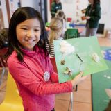 A child holding up her gardening craft