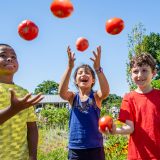 Three children throwing tomato's in the air at the Edible Academy