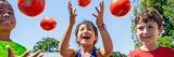 Three children throwing tomato's in the air at the Edible Academy