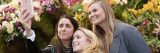 Three women taking a selfie in front of orchids