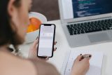 Woman taking notes and holding a phone