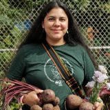 A woman holding vegetables harvested from a community garden.
