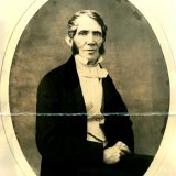 Black and white portrait of John Torrey seated wearing a checked vest and a tie