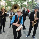 Musicians from Nation Beat performing on a street.