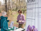 Two people talking in front of Citizen Science banner and table