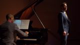 A man singing and another man playing piano.