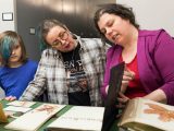 Herbarium staff showing a specimen to two people