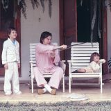 A man with two children sitting in chairs outdoors.