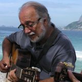 A man playing guitar on a beach.