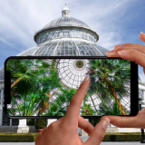 A hand holding a phone up in front of the Conservatory.