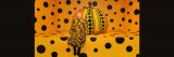 Yayoi Kusama seated in front of a giant black and orange polka-dotted pumpkin sculpture in a room of the same design.