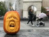 Carved pumpkin face on a wet floor in front of an archway in a city