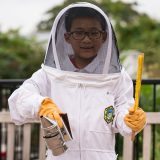 A boy in a beekeeping outfit.