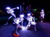 picture of performers wearing light up visors and shiny silver outfits