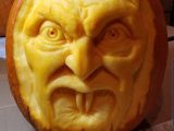 Close up of carved pumpkin face with two fang teeth